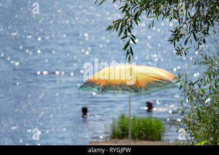 Natürlicher tropischer palm leaf Sonnenschirm und Liege am Strand unter Palmen Schatten mit Blick auf den Strand mit blauem Meer auf der Insel Stockfoto