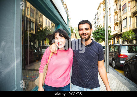 Glücklich und attraktive junge Paar Lachen beim Gehen auf die Straße