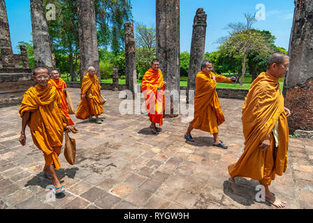 Eine Gruppe Buddhistischer Mönche wandern und lächelnd bei einem Besuch in einem der Buddhismus Tempel und Ruinen von Sukhothai, Thailand, Asien. Stockfoto