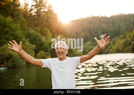 Porträt eines lächelnden älteren Mann stand neben einem See während auf Ferien. Stockfoto