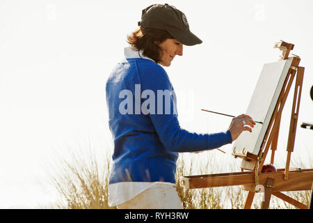 Gerne reife Frau malen ein Bild von einem malerischen Blick auf den Strand. Stockfoto