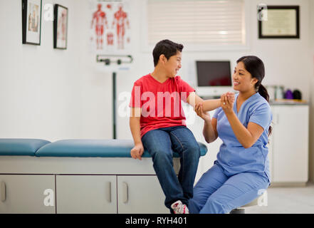 Verspielte Junge seine Muskeln in einer Arztpraxis. Stockfoto