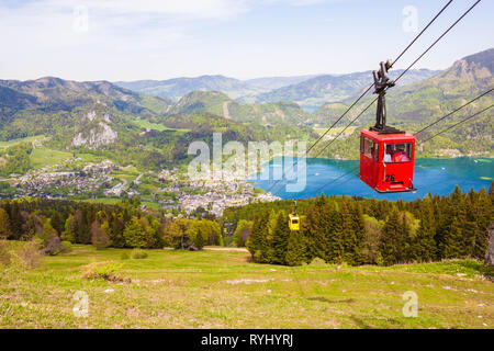 Gelbe und rote Gondeln der Seilbahn Zwoelferhorn (Seilbahn) Reisen nach oben und unten alpine Peak mit Blick auf St. Gilgen, den Wolfgangsee See. Stockfoto