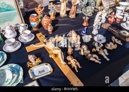 Traunstein, Deutschland - 8 April 2018: Crusifix, Figuren von Putti und Engelchen, porcelian Schale, Figuren und andere alte Sachen zum Verkauf auf einem Flohmarkt Stockfoto