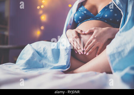 Nicht erkennbare schwangere Frau hielt Bauch zu Hause Stockfoto