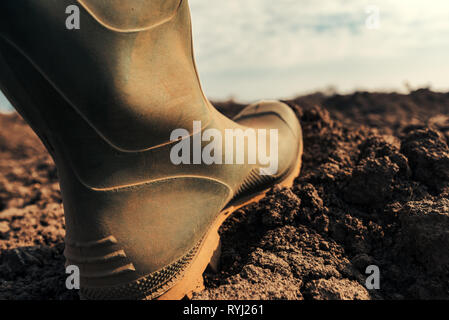 Landwirt in Wellington Gummistiefel macht ersten Schritt im Feld, in der Nähe auf. Beginn der Landwirtschaftlichen Saison und Starten von Aktivitäten auf Ackerland. Stockfoto
