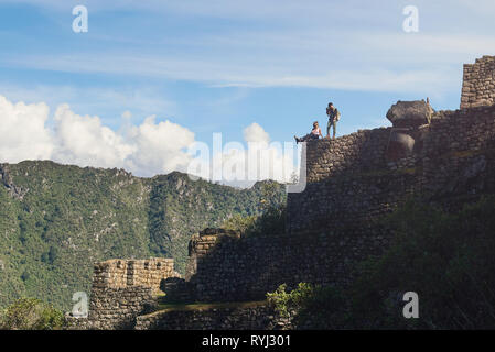 Machu Picchu, Peru - 22. April 2017: Menschen sitzen am Rande von Machu Picchu Ruinen und Fotos Stockfoto