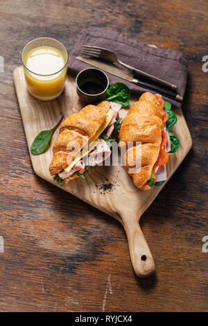 Frühstück croissant Sandwiches mit Orangensaft serviert auf Holzbrett Stockfoto