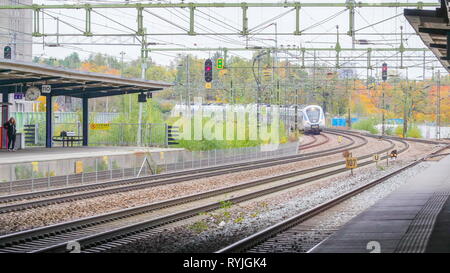 Einen langen weißen Zug nähert sich auf Station in Stockholm Schweden mit der Passagiere warten auf der Station Stockfoto