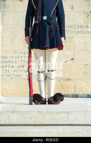 Tracht und Gewehr der Beine von Evzone Präsidentengarde vor dem Parlamentsgebäude und Grab des unbekannten Soldaten in Athen, Griechenland. Ver Stockfoto