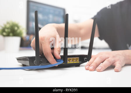 Man verbindet das Internet Kabel an die Buchse des Routers. Schnelle und kabellose Internet Konzept Stockfoto