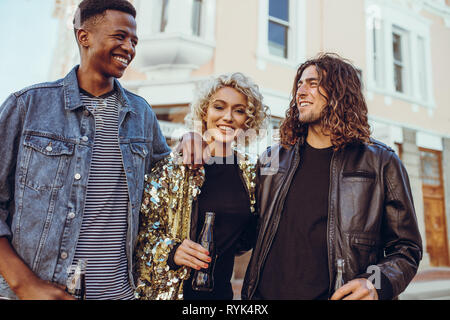 Gruppe von drei jungen Freunde zu Fuß die Straße der Stadt. Junge Männer und Frauen in der Stadt. Stockfoto