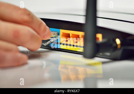 Hand auf Wireless Router und Netzwerk Kabel Stockfoto