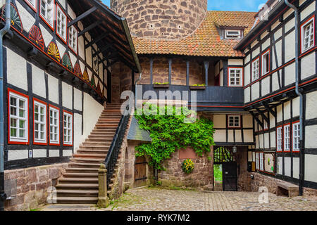 Blick auf den gepflasterten Schlosshof aus dem Inneren der Burg Ludwigstein in Deutschland. Die Fachwerkhäuser mit schönen Schnitzereien sind... Stockfoto