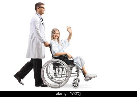 Volle Länge Schuß eines jungen männlichen Arzt eine Patientin im Rollstuhl isoliert winken auf weißem Hintergrund Stockfoto