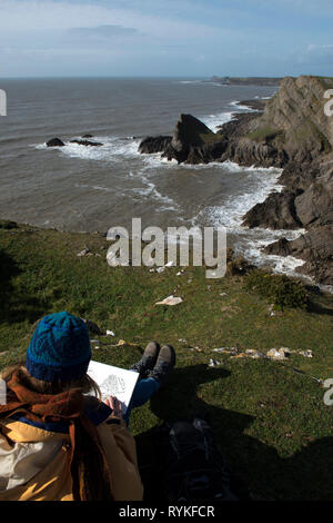 Mädchen Malerei Blick über die Klippen zu Würmer aus der Bube auf Gower Stockfoto