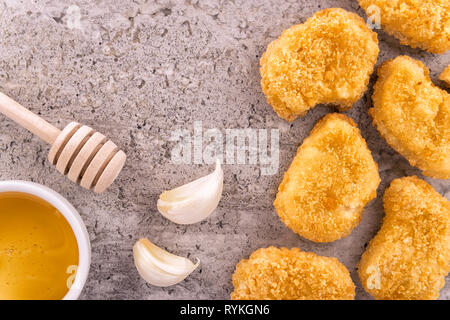 Chicken Nuggets mit Knoblauch und Honig auf ein konkretes Textur Hintergrund. Direkt oberhalb. Stockfoto