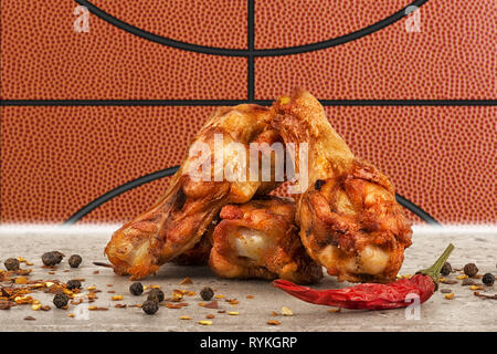 Chicken Wings mit red hot chili Pfeffer, Salz und Pfeffer. Basketball Ball Bild im Hintergrund. Stockfoto