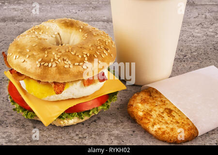 Breakfast Sandwich mit Kaffee und Hash Brown auf konkrete Tabelle. Bagle, Eier, Käse und Speck. Stockfoto