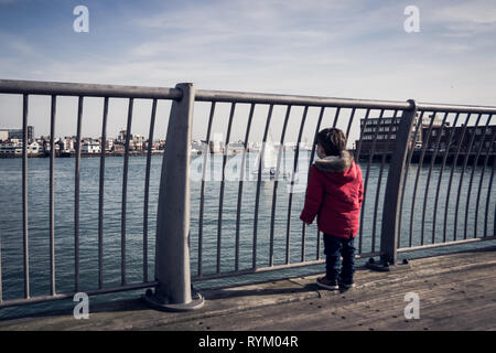 Kleine Jungen im roten Mantel an Boote und Yachten Portsmouth Harbour Blick von der Brücke in Gosport, Großbritannien Stockfoto