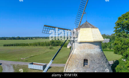 Ein Mann, der Holzschindeln auf die Windmühlen alten grossen Dach mit Blick auf die Bäume auf der Rückseite Stockfoto