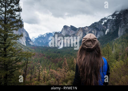 Junge weibliche Reisende zurück stehen und am Wald, in den Bergen, Wasserfall und Bäume. Mädchen auf dem Hintergrund der erstaunlichen Tal im Yosemite Park, USA. Stockfoto