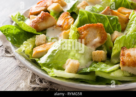 Caesar Salat mit dem Salat, Hühnchen und Croutons auf Holztisch. Schließen Stockfoto