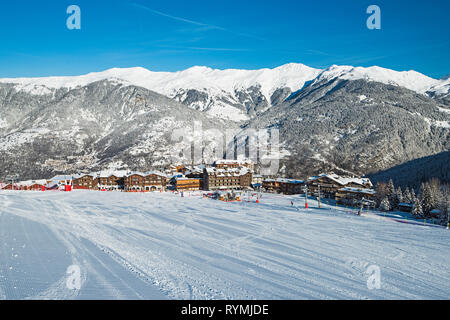 Skifahrer auf einem Hang Skipiste im Winter alpine Mountain resort mit Dorf im Hintergrund Stockfoto