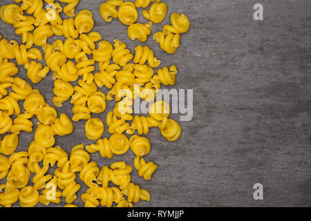 Menge ganze rohe Nudeln funghetto Sorte mit Copyspace flatlay am grauen Stein Stockfoto