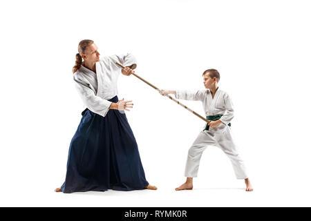 Mann und jugendlich Junge Kampf mit holzschwert an Aikido Training in Martial Arts School. Gesunder Lebensstil und Sport Konzept. Fightrers in weißen Kimono auf weißem Hintergrund. Karate Männer in Uniform. Stockfoto