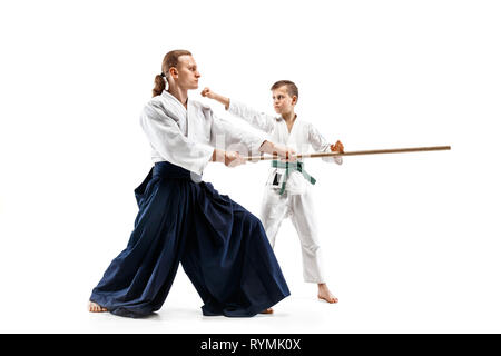 Mann und jugendlich Junge Kampf mit holzschwert an Aikido Training in Martial Arts School. Gesunder Lebensstil und Sport Konzept. Fightrers in weißen Kimono auf weißem Hintergrund. Karate Männer in Uniform. Stockfoto