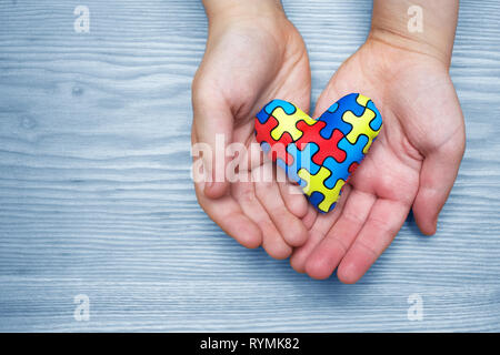 Welt Autismus Bewußtsein Tag, Puzzle oder Stichsäge Muster auf Herz mit Hände des autistischen Kindes Stockfoto