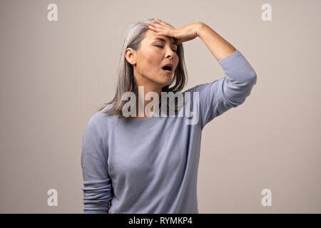 Mongolin mit grauem Haar zeigt Emotionen des Leidens. Stockfoto