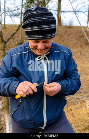 Eine Frau Gärtner schneidet einen Clip aus Holz für die Impfung mit einem scharfen Messer Stockfoto