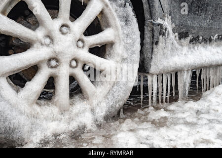 Eisansammlung und Eiszapfen auf einem Auto und close-up auf einem Rad, in Montreal, Kanada. Stockfoto