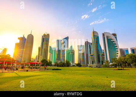 Doha West Bay Hochhäuser bei Sonnenuntergang vom grünen Rasen eines Parks an corchiche Promenade. Moderne Wolkenkratzer der Skyline von Doha in Katar, Naher Osten Stockfoto