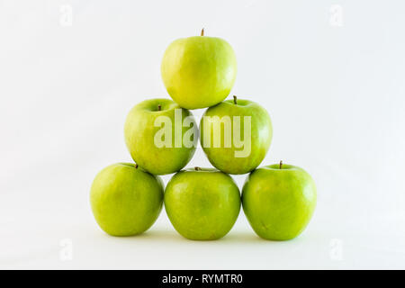Grüne Granny Smith Äpfel in einem Dreieck oder Pyramide gestapelt, auf weißem Hintergrund. Stockfoto
