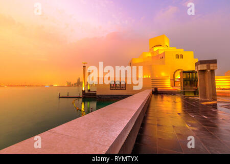 Meer und West Bay von Doha Skyline entlang der Corniche in der katarischen Hauptstadt mit Dhow-hafen Beleuchtung an der blauen Stunde. Doha in Katar. Naher Osten, Arabische Stockfoto