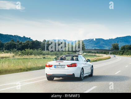 Schiltach, Deutschland - May 10, 2018: Die deutsche Autobahn mit luxuriösen BMW Cabrio Cabriolet Auto schnell auf der Landstraße an einem sonnigen Tag mit Schwarzwald Berge im Hintergrund Stockfoto