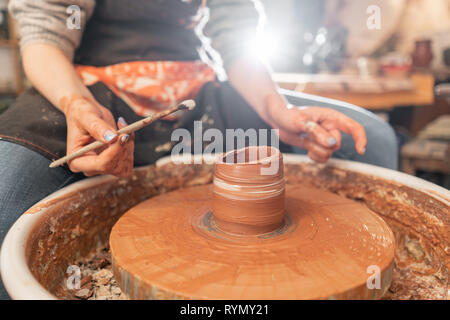 Handwerker Hände Töpfern Schüssel. Frau an der Töpferscheibe. Family Business Shop formt Topf aus Ton Sicht von oben. Stockfoto