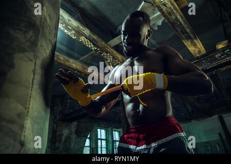 Afro-amerikanische Boxer wickelt sich die Hände mit gelben Bandage Stockfoto