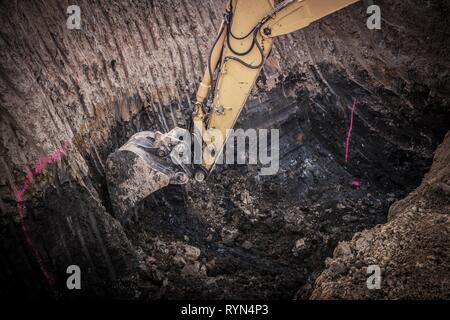 Bau Ausgrabungsstätte. Bagger Graben in großer Masse Loch. Stockfoto