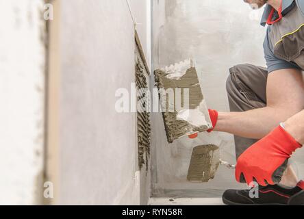 Arbeitnehmer moderne keramische Fliesen. Kaukasische Fliese Installer bei der Arbeit. Bad Renovieren. Stockfoto