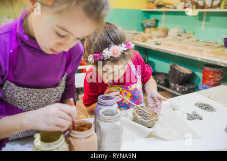 Zwei kleine jungen Künstlerin Mädchen malen Mit Pinsel Ton Vase auf dem Tisch in Keramik studio Stockfoto