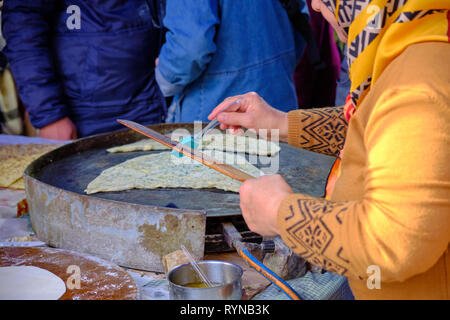 Lokale Frau mit Kopftuch Vorbereitung türkische Pfannkuchen (gözleme) für Kunden, die an einer Messe in Antalya, Türkei Stockfoto