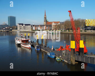 Bremen, Deutschland - 14. Februar 2019 - Pier mit mehreren kleinen Schiffe und hellen roten schwimmenden Kran und die Skyline der Stadt mit Weser Tower und St, Stepha Stockfoto