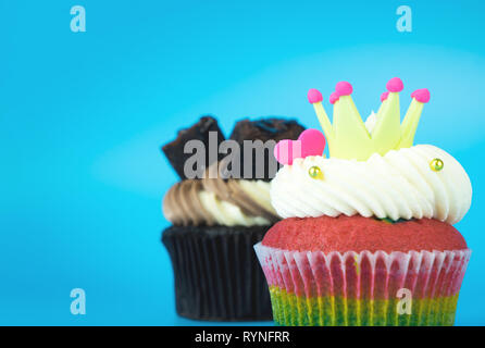 König Cupcake Rainbow Muffin mit Chocolate Brownie Cupcake auf blauem Hintergrund Stockfoto