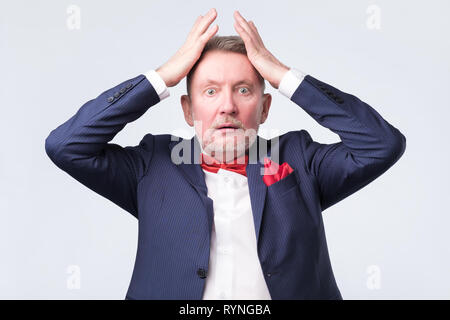 Senior zornigen Mann mit der Hand am Kopf auf Studio Wand Stockfoto