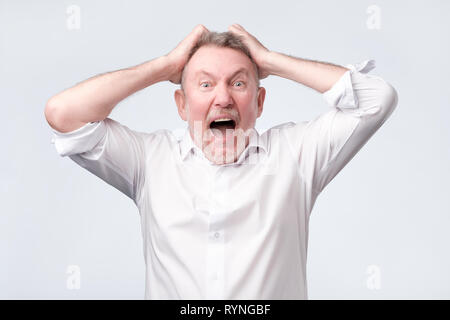 Senior zornigen Mann mit der Hand am Kopf auf Studio Wand Stockfoto