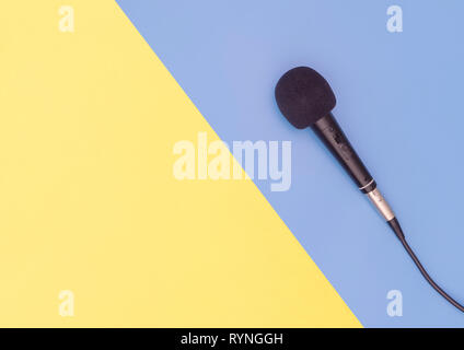Schwarz Mikrofon auf Blau Gelb Hintergrund für Musik Konzept Stockfoto